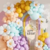 Prezentare eleganta pentru un set arcada baloane aniversare pastel cu flori margareta, montat in nuante de bleu, crem, mov si galben.