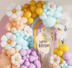 Prezentare eleganta pentru un set arcada baloane aniversare pastel cu flori margareta, montat in nuante de bleu, crem, mov si galben.