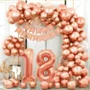 Prezentare eleganta pentru un set arcada baloane majorat rose gold, montat asimetric cu cifre gigant 18 si banner Happy Birthday.