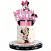 Topper pentru tort cu sclipici roz reprezentand mesajul Happy Birthday si personajul Minnie Mouse pozitionat in partea de sus.