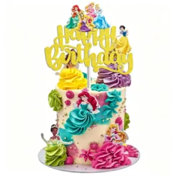 Topper pentru tort cu sclipici auriu reprezentand mesajul Happy Birthday si un grup de printese din basme pozitionat in partea de sus a unui tort colorat.