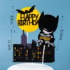 Set de decoratiuni pentru tort cu tema Batman, incluzand silueta neagra a orasului, luna galbena cu Happy Birthday si personajul decorativ.