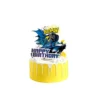 Topper de carton pentru tort cu supereroul Batman, masina Batmobil si textul Happy Birthday, asezat pe un tort galben.